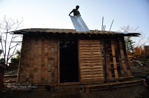 A tribal man reparing his home